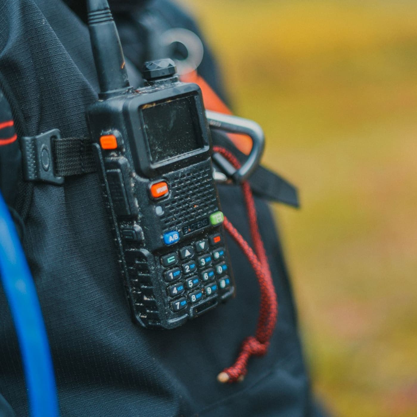 Dual-band handheld radio clipped to a pack strap outdoors